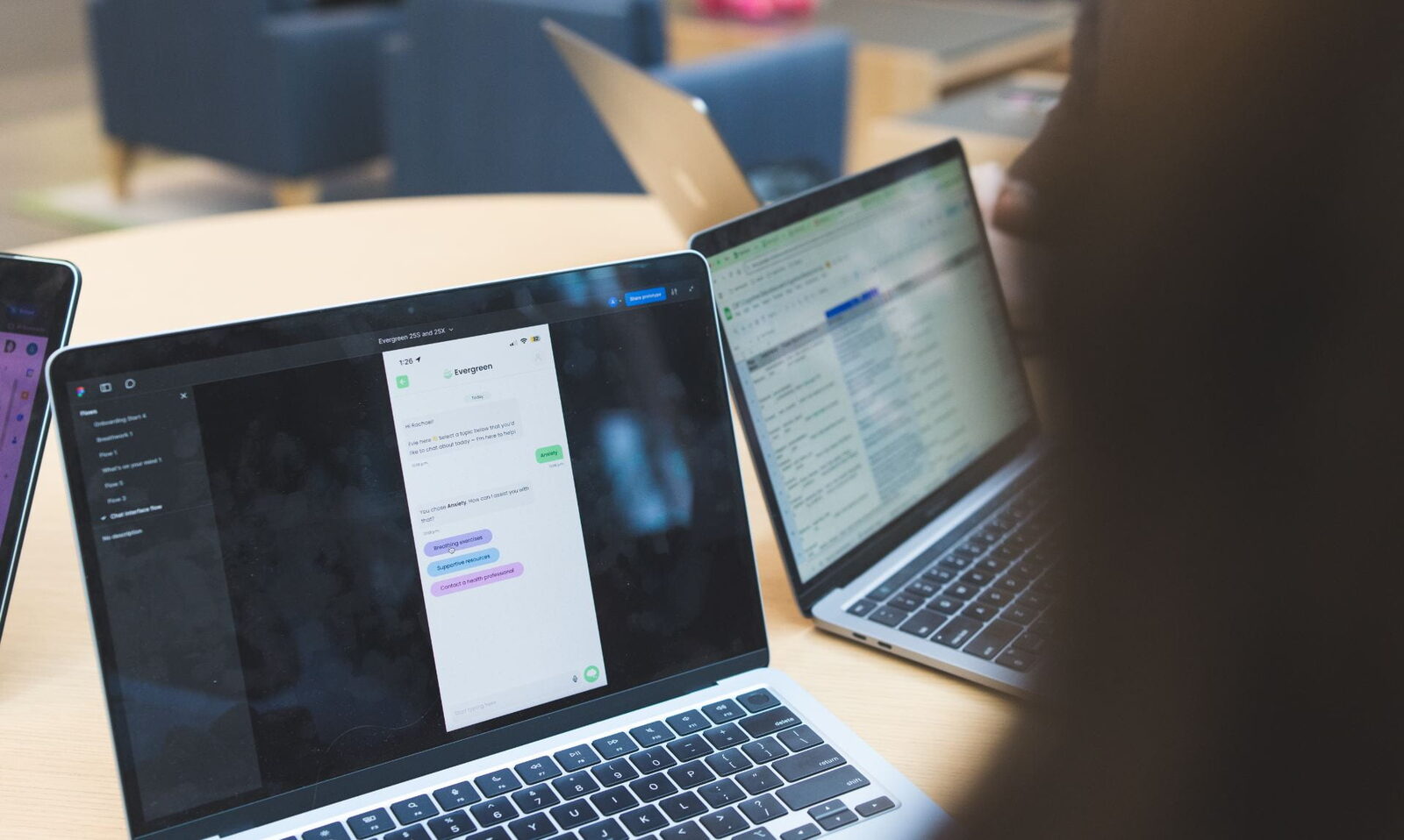 Laptops on a table showing an Evergreen chat prototype in a design tool, as students work on the platform together