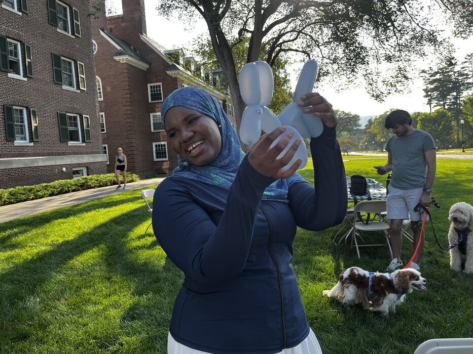 A student proudly holding up a balloon animal at the summer wellness party
