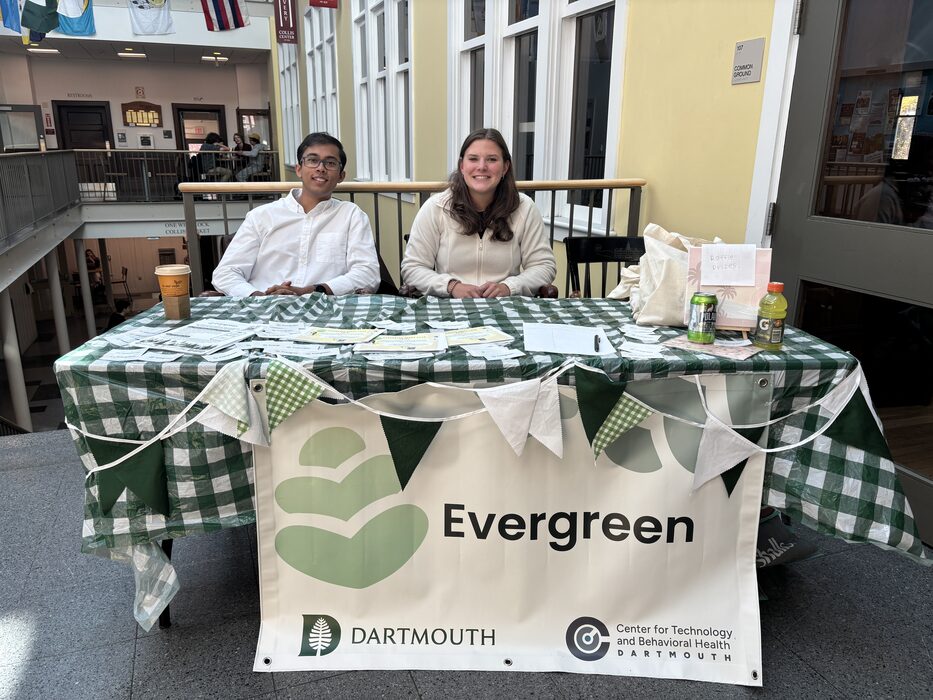 Team members at an Evergreen welcome table with the project banner