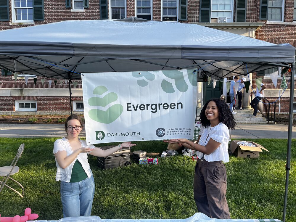 Two team members holding the Evergreen banner at a campus event