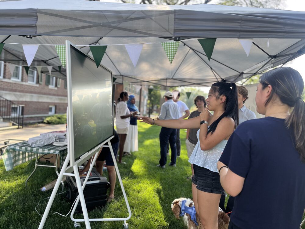 Team members sharing food under the tent at the summer wellness party